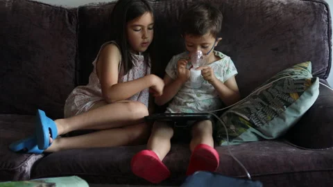 Little boy with vaporizing mask using a digital tablet with his sister. Stock Footage 200835724