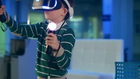 Little boy in virtual reality headset holding move motion controllers Vídeos de archivo 76858329