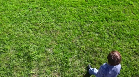 Little boy walk backward by grass plot, and then return Stock Footage 10807894