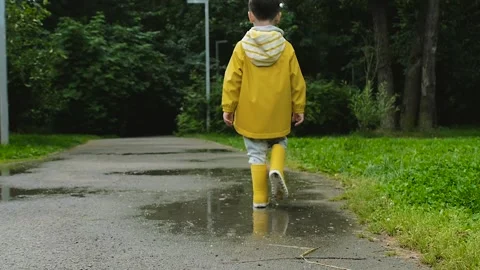 Little boy walking in a raining park Stock Footage