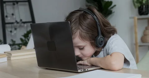 Little boy wearing headset learning online at laptop via video call, but he can Stock Footage 162478794
