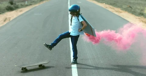 Little boy wearing helmet and styrofoam wings standing on a skateboard Stock Footage
