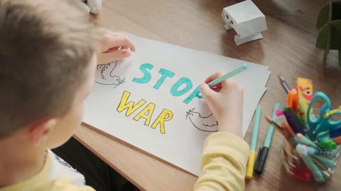 A little boy writes on paper a message to stop the war. No war, stop war Stock Footage 177833607