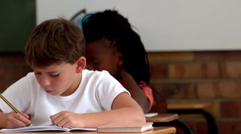 Little boy writing in notepad in classroom Stock Footage 40406977