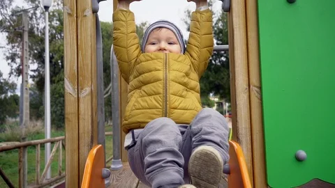 Little boy in a yellow jacket playing on a playground Stock Footage 89773548