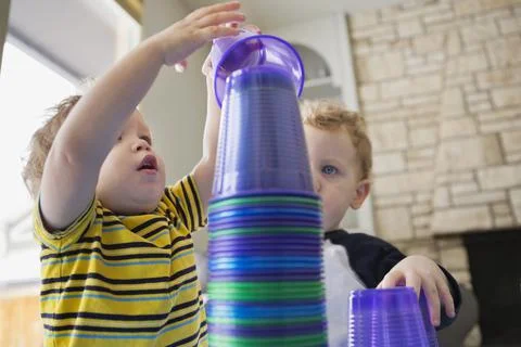 Little boys stacking plastic cups at home Stock Photos