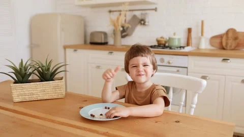 A little caucasian boy eats krunchy breakfast and enjoys it at kitchen table. Stock Footage 170522723