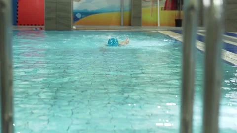 Little caucasian boy wearing goggles swimming in a pool and getting out from 스톡 동영상 166399960