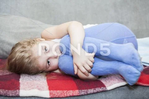 Little caucasian defenseless child huddled on the couch Stock Photos