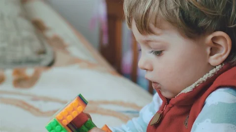 Little charming boy playing with the constructor toys on couch in living room. Vídeo Stock 128751041