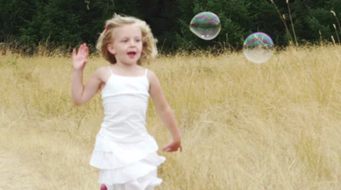 A little chases down some bubbles. Medium shot. Stock-Footage 33869676