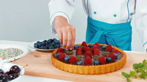 Little chef cook decorating the cake using blueberry Stock Footage 66199834