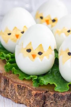 Little chicken in nest, deviled eggs served with salad on wooden board, ver.. Foto stock