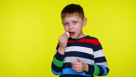 Little child boy eats chocolate bar on a yellow background with copy space Stock Footage 130490048