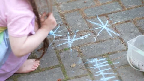 Little child creating sidewalk chalk art on brick pavement outside Stock Footage 335587701