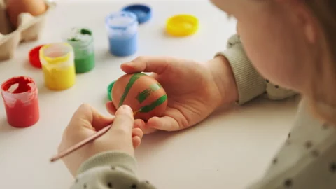 Little child decorates Easter eggs with colored green paint Stock Footage 168713088