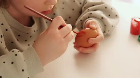Little child decorates Easter eggs with colored red food paint. Stock Footage 168713797