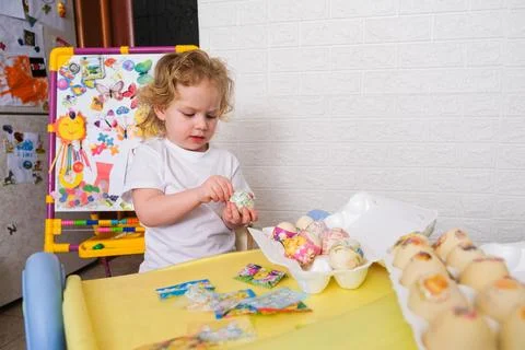 Little child decorating Easter egg at table. Creative kid preparing holiday Stock Photos