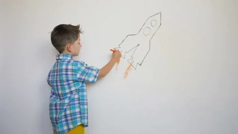 Little child drawing thr rocket on white wall Stock Footage 93539756