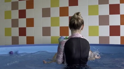 A little child floating on the back with the coach in the pool Vídeo Stock 85267835