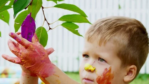 A little child, a four-year-old boy playing, painting with finger paints Stock Footage 80441333