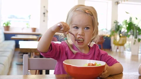 Little child girl eats vegetable salad in restaurant Stock Footage 317170657