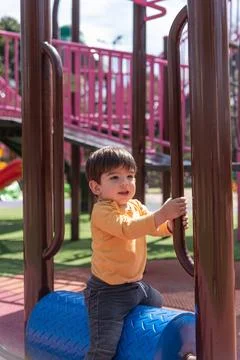 Little child having fun while playing at the playground in the park. Stock Photos