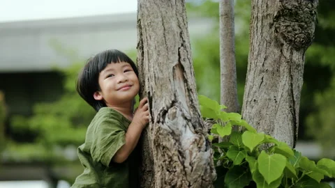 Little child is hugging a tree while running and playing in the park. Stock Footage 209767183