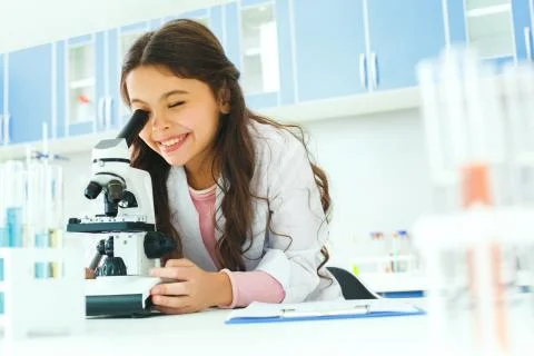 Little child with learning class in school laboratory using microscope Stock Photos