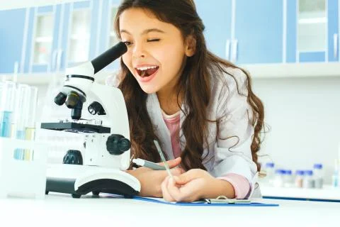 Little child with learning class in school laboratory looking in microscope Stock Photos