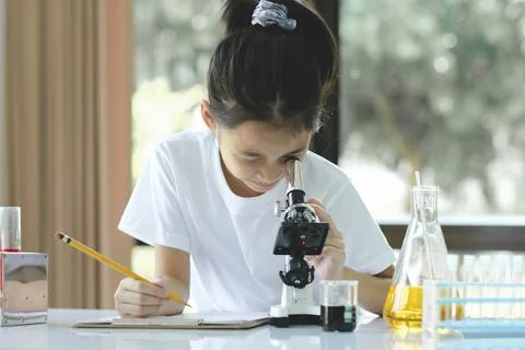 Little child with learning class in school laboratory using microscope Stock Photos