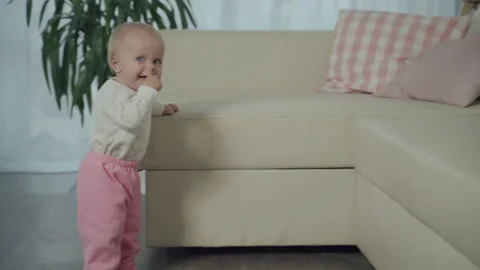 Little Child Learns Walking Taking First Steps Holding Furniture Sofa Hand Stock Footage 142286052