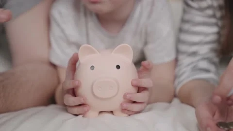 Little child with mother and father throw coins of money at pig, happy family Stock Footage