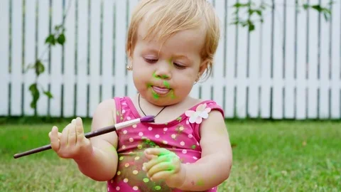 A little child, a one-year-old girl playing, painting with finger paints Stock Footage 80441269