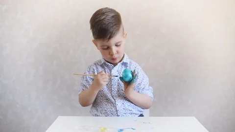 A little child paints an one easter egg at the table on a white background. Stock Footage 121513410