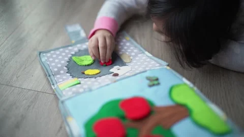 Little child play snapping button on montessori busy book toy Stock Footage 159126024
