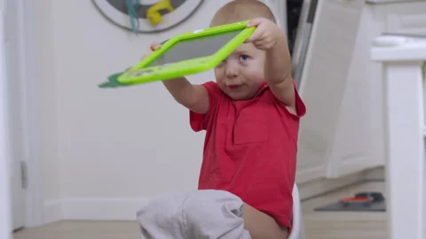 Little child playing with drawing tablet 3-year-old boy sitting on potty Stock Footage 263703232