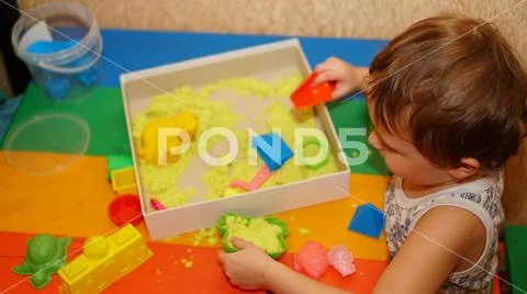 Little child playing with forms for sand. Boy sitting on the chair at