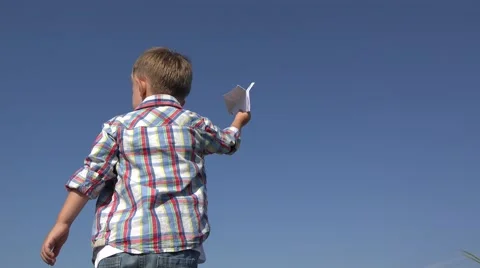 Little child playing with a paper toy plane, real airplane passing over boy head Stock Footage