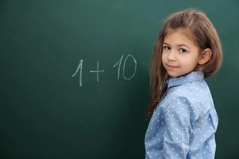 Little child solving math sum near chalkboard Stock Photos