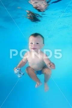Little child swims underwater in the swimming pool Stock Photos