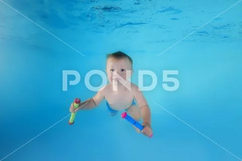 Little child swims underwater in the swimming pool Stock Photos