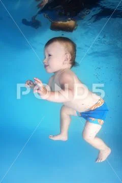 Little child swims underwater in the swimming pool Stock Photos