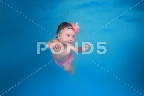 Little child swims underwater in the swimming pool Stock Photos