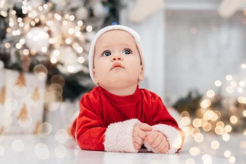 Little child under Christmas tree. baby boy in Santa Claus hat with gifts und Stock Photos