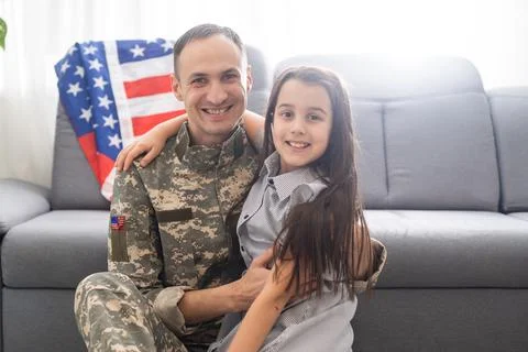 Little child is very happy her father came back from army. Little kid is hugging Stock Photos
