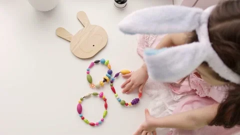 Little child is wearing Easter bunny ears and playing a color wreaths Stock Footage 171370569