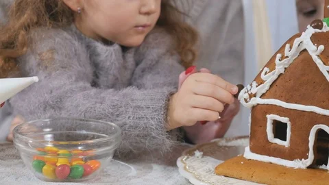 Little children decorates a gingerbread house with a colorful candies Stock Footage