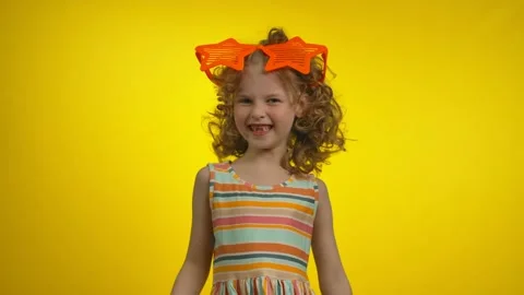 Little curly girl in funny star glasses with charming toothless smile is dancing Stock Footage