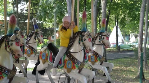 Little cute 5 years old girl ride horse on the old fashioned french carousel Stock Footage 220173463